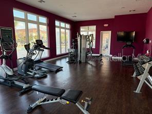 A gym with dark wood floors, purple walls, exercise equipment, and large windows — 8962 SILVER PLACE, KISSIMMEE, FL