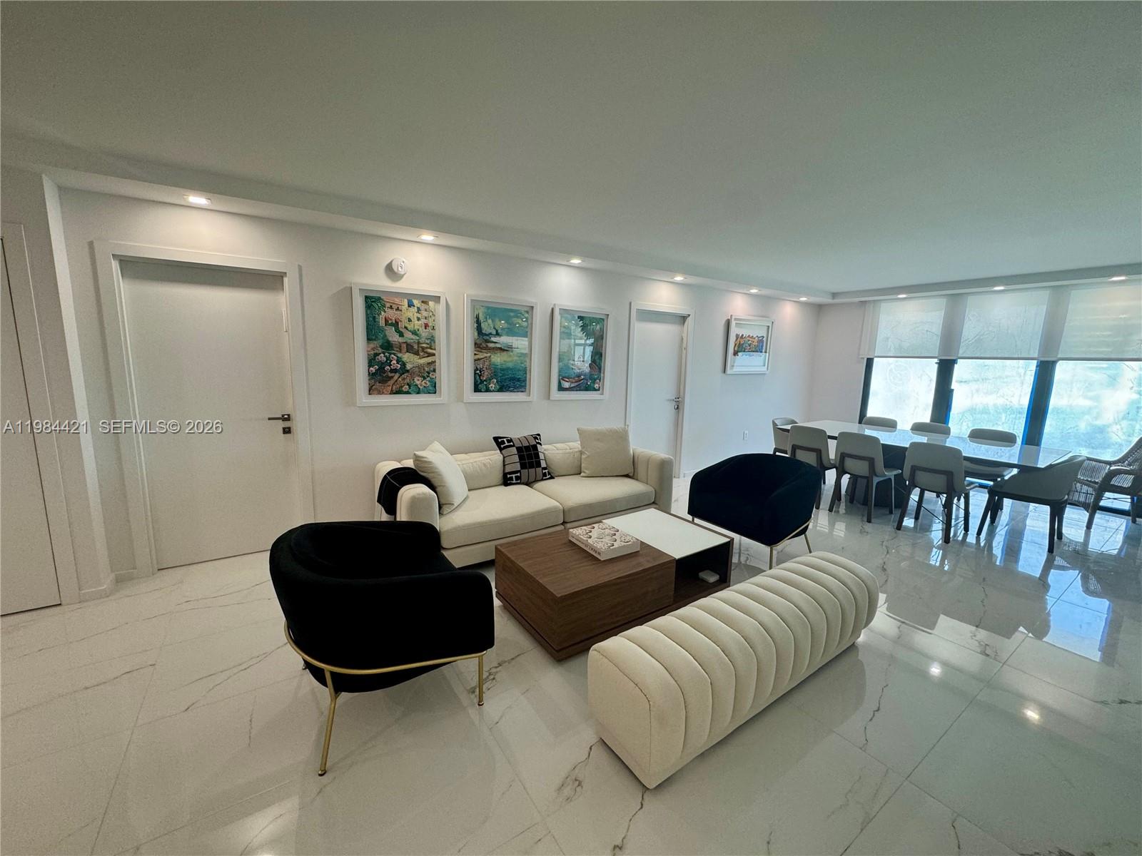 A modern living and dining area features white marble floors, neutral furniture, and framed artwork — 9801 Collins Ave # 20E, Bal Harbour FL 33154, BAL HARBOUR, FL