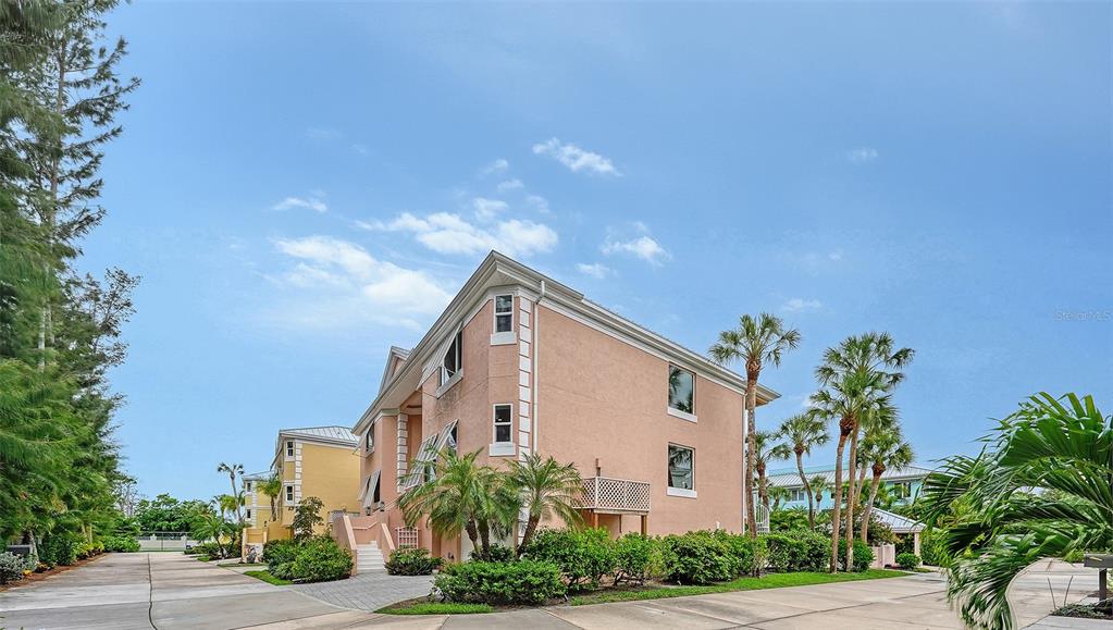 A multi-story peach-colored building with palm trees and a paved driveway under a blue sky — 3942 HAMILTON CLUB CIRCLE UNIT 13, SARASOTA, FL