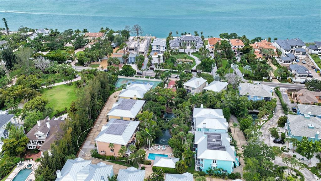 An aerial view shows a multi-story peach-colored building with a metal roof near a pool — 3942 HAMILTON CLUB CIRCLE UNIT 13, SARASOTA, FL