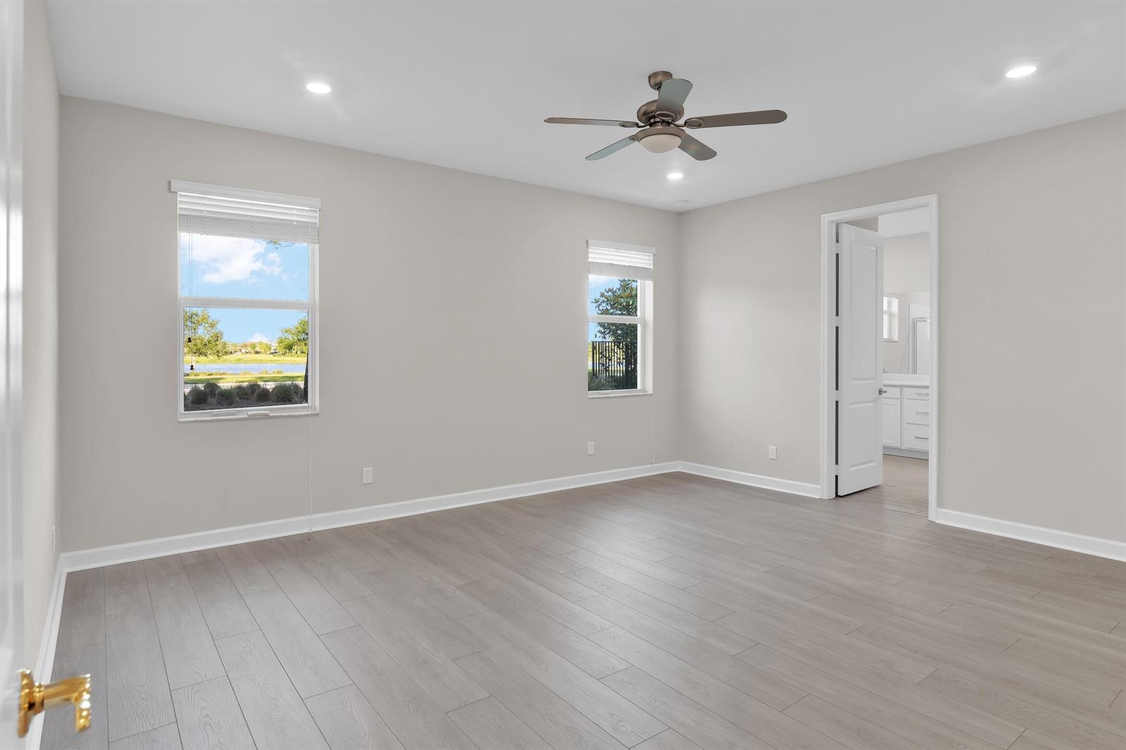 A bedroom with light gray walls, wood-look flooring, a ceiling fan, and two windows — 1168 Sterling Pine Place, Loxahatchee FL 33470, LOXAHATCHEE, FL