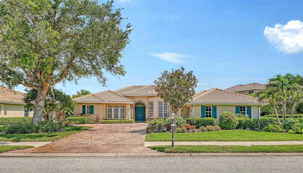 A single-story house with a brick driveway, tile roof, and green shutters under a blue sky — 225 PESARO DRIVE, NORTH VENICE, FL