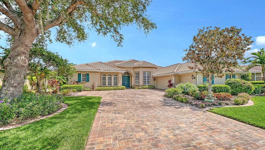 A single-story house with a brick paver driveway and a large oak tree — 225 PESARO DRIVE, NORTH VENICE, FL