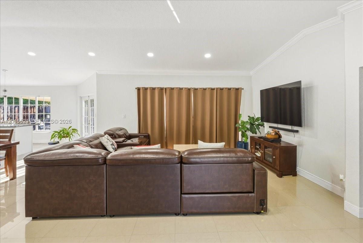 A living room features a large brown leather sectional sofa, a television, and tile flooring — 16540 SW 145th Ct, Miami FL 33177, MIAMI, FL