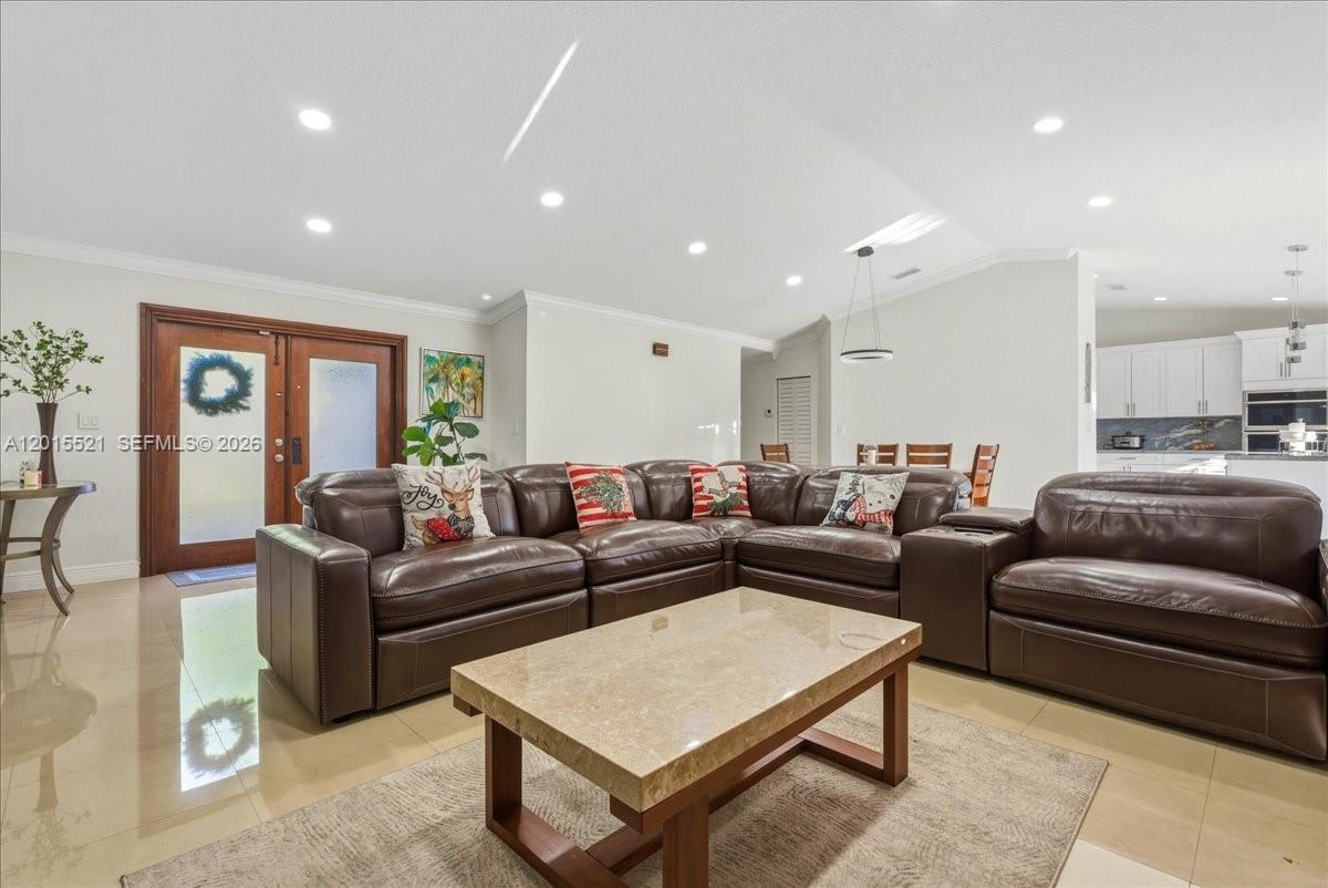 A living room features a large brown leather sectional, a stone coffee table, and tile flooring — 16540 SW 145th Ct, Miami FL 33177, MIAMI, FL