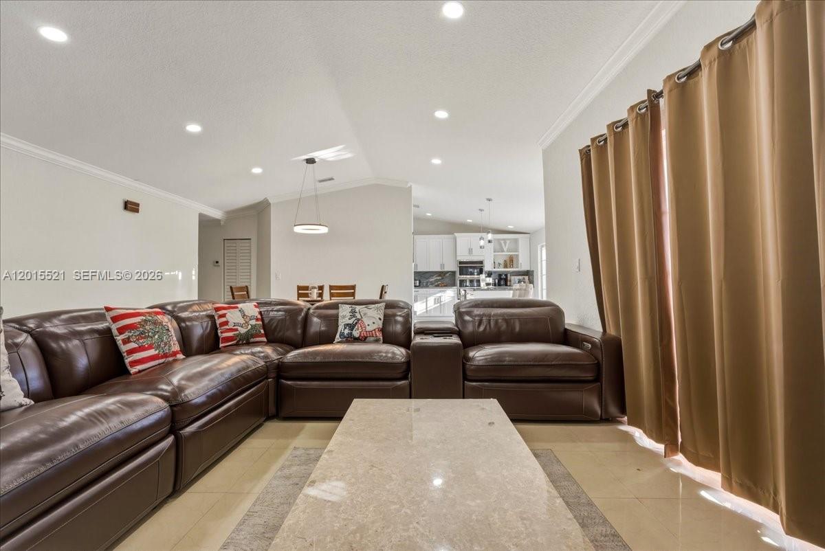 A living room features a large brown leather sectional, a stone coffee table, and curtains — 16540 SW 145th Ct, Miami FL 33177, MIAMI, FL