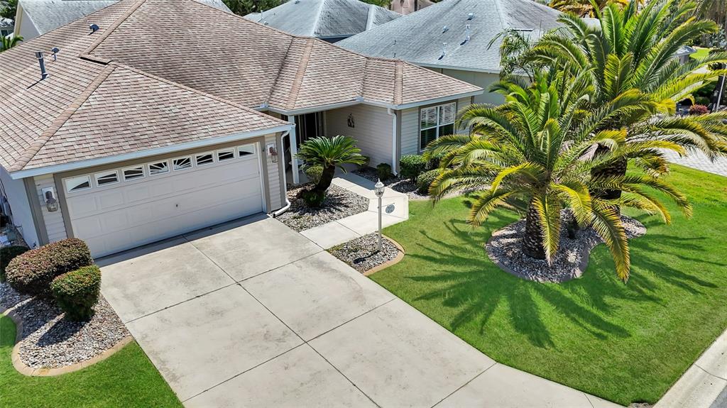 An aerial view shows a single-story house with a two-car garage and a palm tree — 934 MOSES LOOP, THE VILLAGES, FL