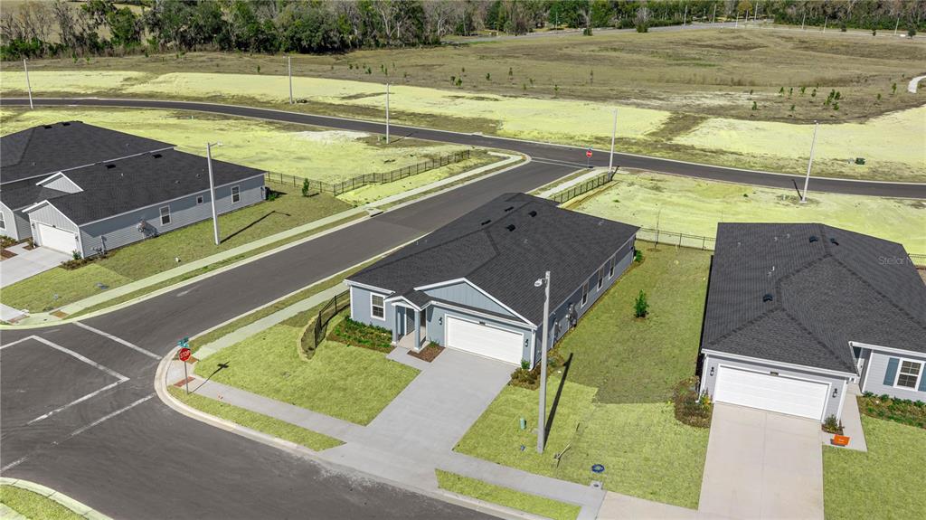 An aerial view shows three suburban houses with dark roofs and driveways on a corner lot — 8814 SW 69TH TERRACE, OCALA, FL