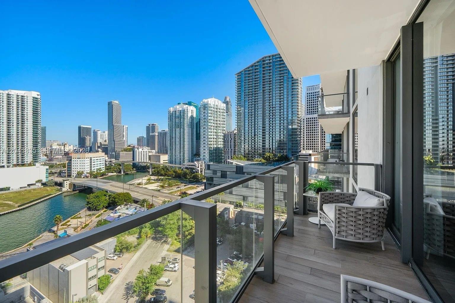 A high-rise balcony with glass railings overlooks a city skyline, a river, and a highway — 88 SW 7th St # 1212, Miami FL 33130, MIAMI, FL
