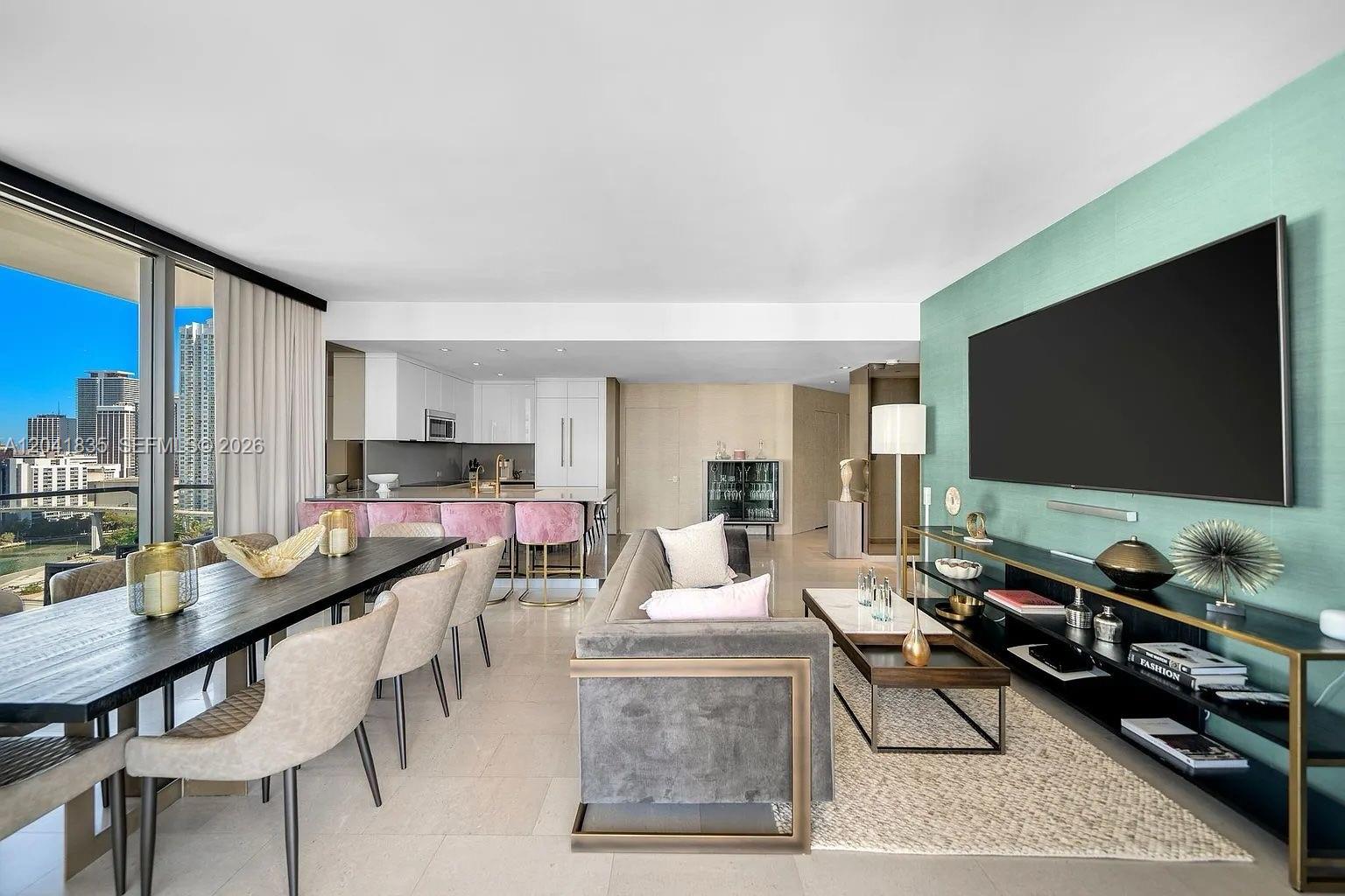 An open-concept living and dining area features a teal accent wall, modern furniture, and city views — 88 SW 7th St # 1212, Miami FL 33130, MIAMI, FL