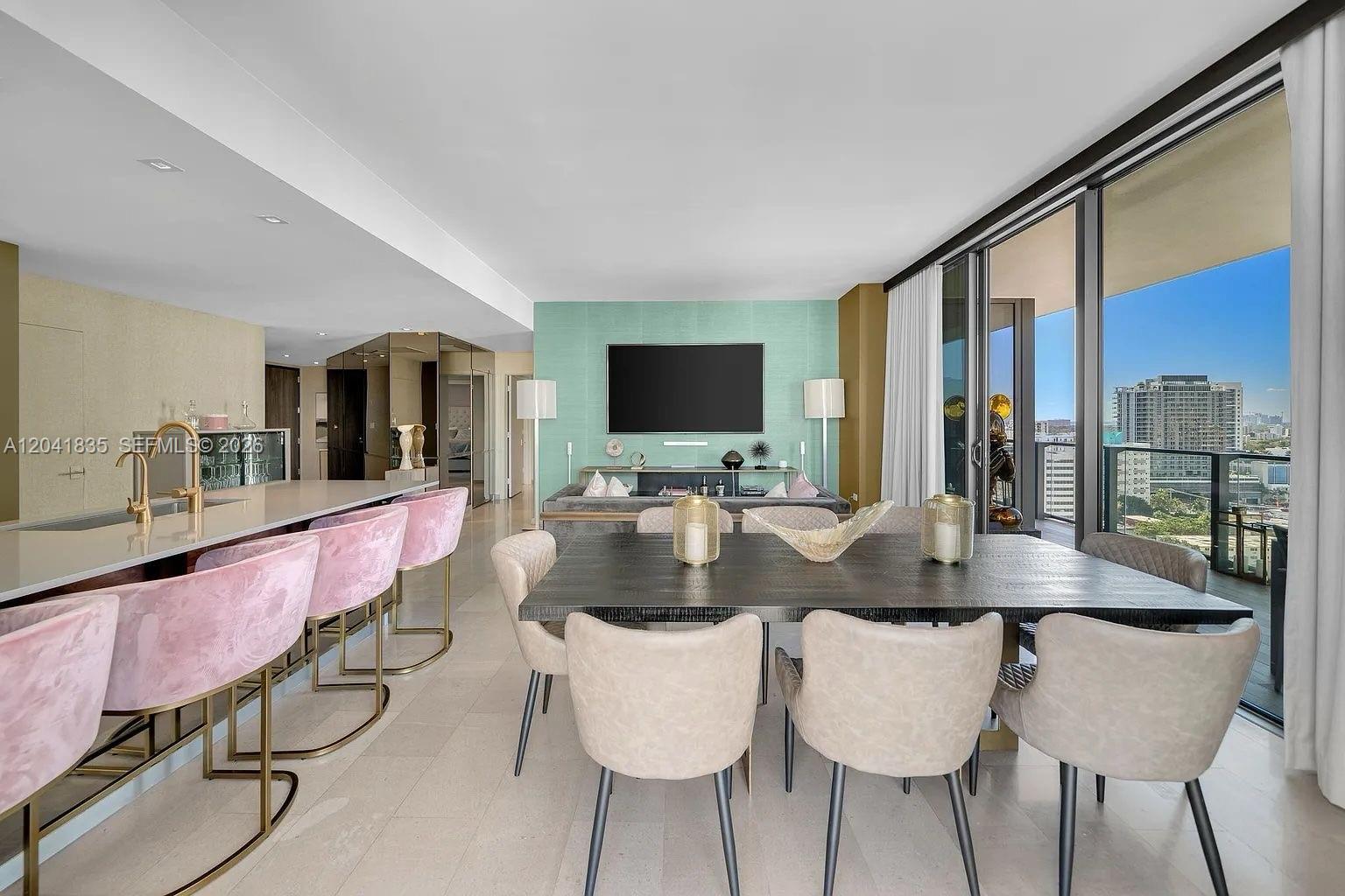 A modern open-plan living and dining area features pink bar stools and a balcony view — 88 SW 7th St # 1212, Miami FL 33130, MIAMI, FL