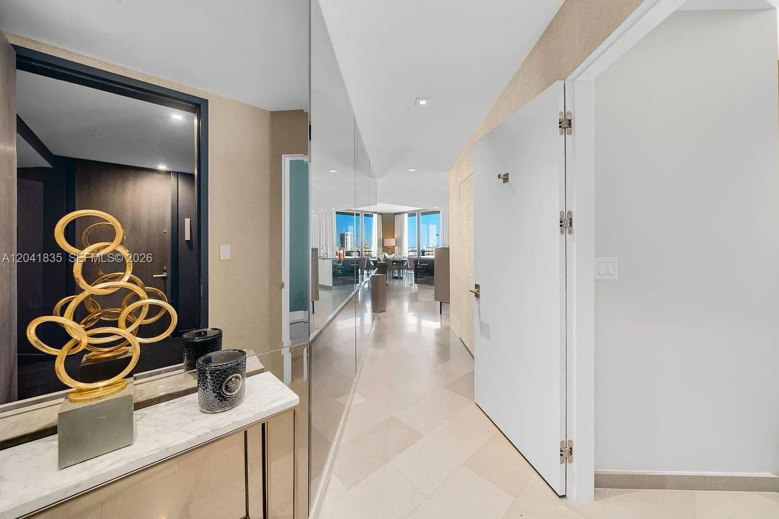 A marble console table with a gold sculpture sits in a mirrored entryway hallway — 88 SW 7th St # 1212, Miami FL 33130, MIAMI, FL