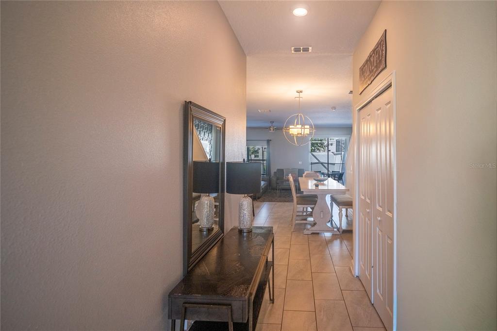 A hallway with a console table and mirror leads to a dining area and living room — 230 OCEAN COURSE AVENUE, DAVENPORT, FL