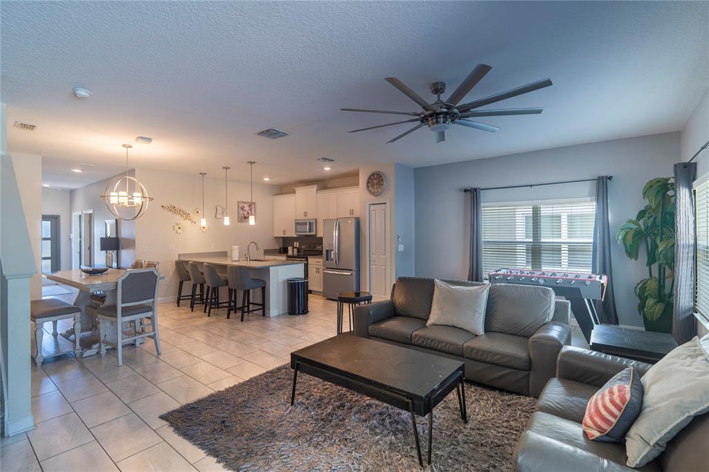 An open-concept living room and kitchen featuring tile flooring, gray sofas, and a dining area — 230 OCEAN COURSE AVENUE, DAVENPORT, FL