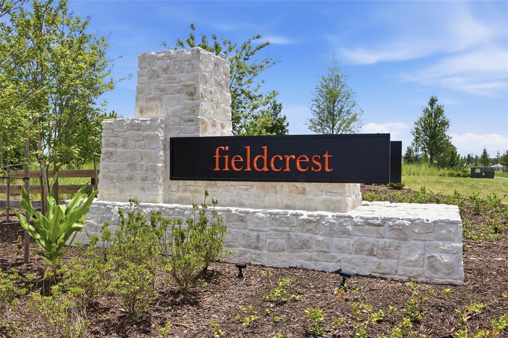 A stone monument sign with the name fieldcrest stands in a landscaped garden area — 37114 SAGEMOOR DRIVE, ZEPHYRHILLS, FL