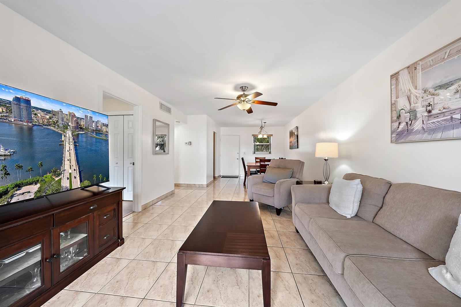 A living room features tile flooring, a beige sofa, a television, and a ceiling fan — 701 Lori Drive # 206, Palm Springs FL 33461, PALM SPRINGS, FL