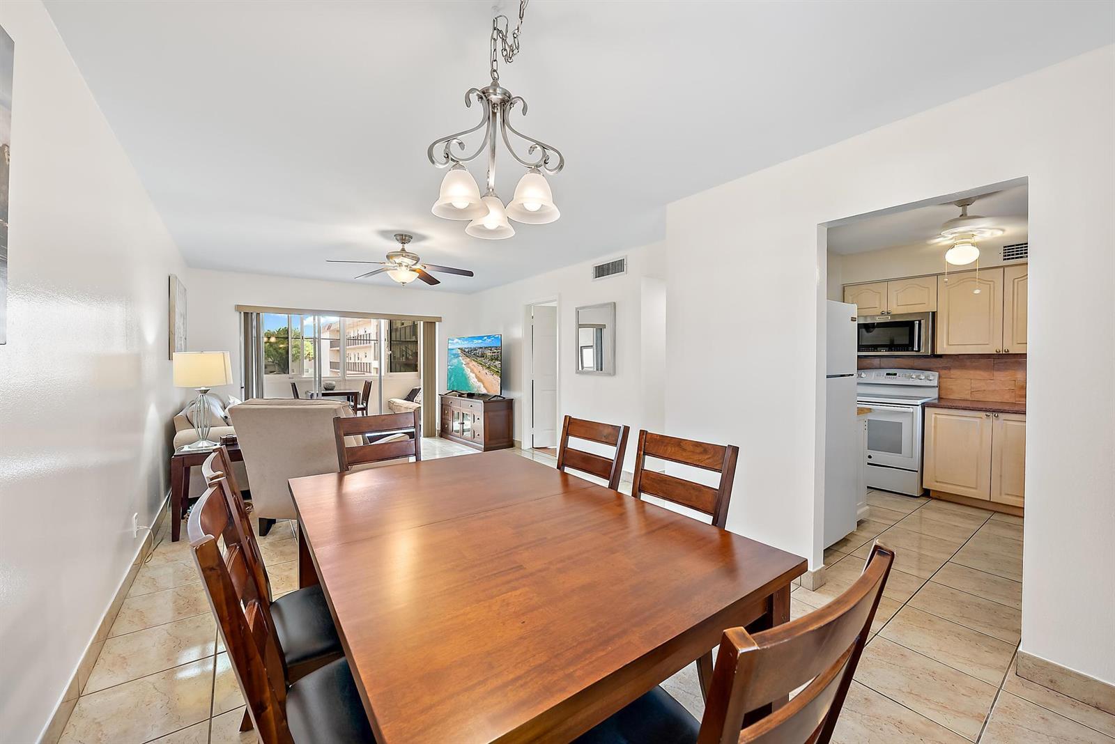 A dining room with a wooden table and chairs opens into a kitchen and living area — 701 Lori Drive # 206, Palm Springs FL 33461, PALM SPRINGS, FL