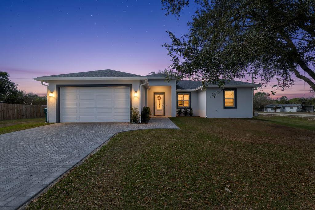 A single-story house with a paved driveway, a white garage, and a front entrance at dusk — 3573 NW 18th Avenue, Okeechobee FL 34972, OKEECHOBEE, FL