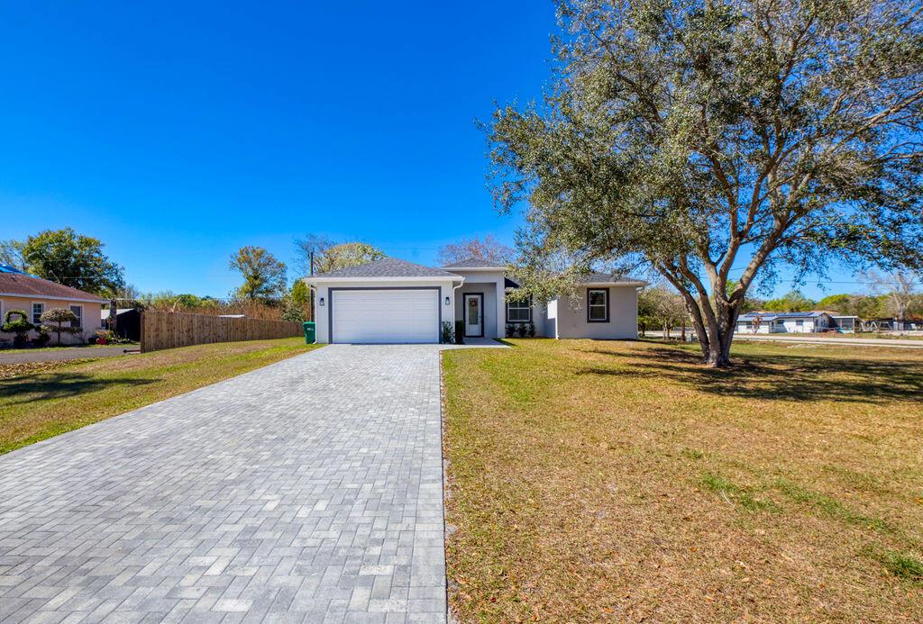 A single-story house with a paved driveway, white garage door, and a large oak tree — 3573 NW 18th Avenue, Okeechobee FL 34972, OKEECHOBEE, FL