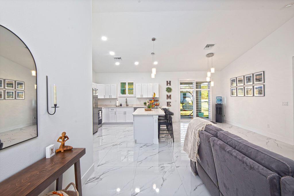 An open-concept kitchen and living area features white cabinetry, a marble island, and tile flooring — 3573 NW 18th Avenue, Okeechobee FL 34972, OKEECHOBEE, FL