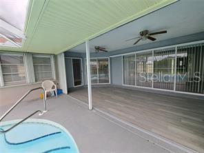 A covered patio features a hot tub, ceiling fans, and sliding glass doors to the home — 26 CLINTWOOD AVENUE, ENGLEWOOD, FL