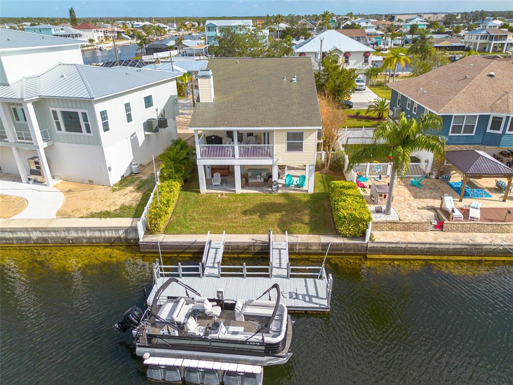 An aerial view shows a yellow house with a boat dock and pontoon boat — 4207 DES PREZ COURT, HERNANDO BEACH, FL