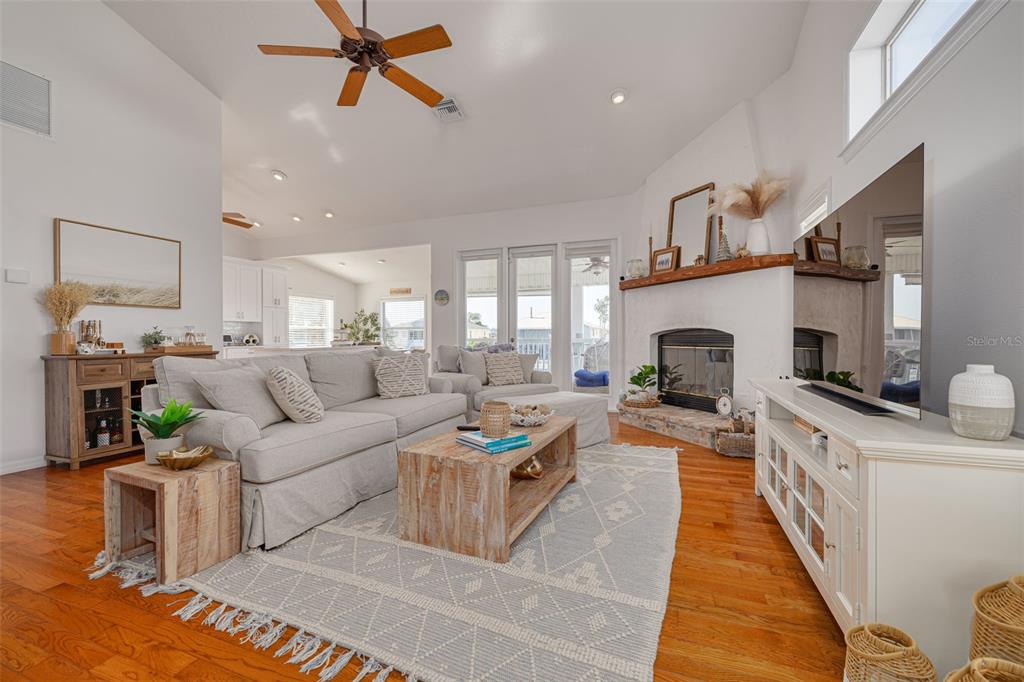 A living room features a fireplace, light-colored sofa, wooden coffee table, and hardwood floors — 4207 DES PREZ COURT, HERNANDO BEACH, FL