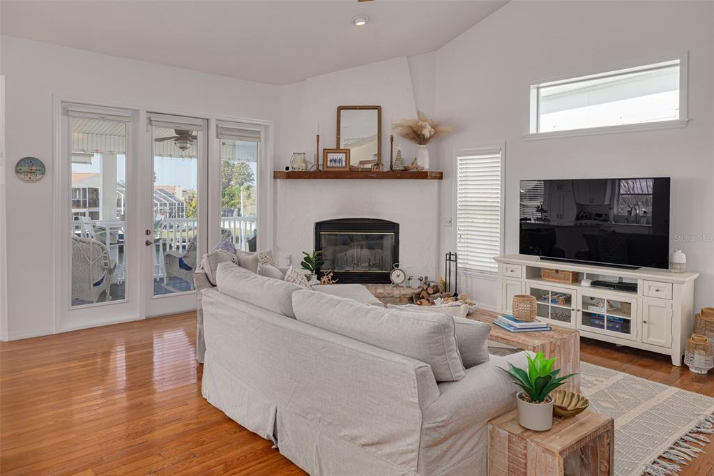 A living room features a fireplace with a wood mantel, hardwood floors, and glass doors — 4207 DES PREZ COURT, HERNANDO BEACH, FL