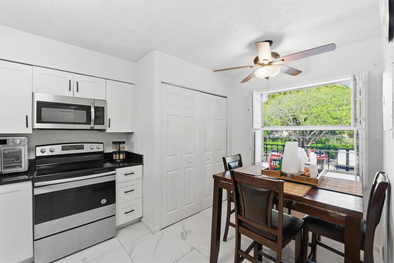 A kitchen with white cabinets, stainless steel appliances, and a dining table by a window — 260 NW 76th Avenue # 207, Margate FL 33063, MARGATE, FL