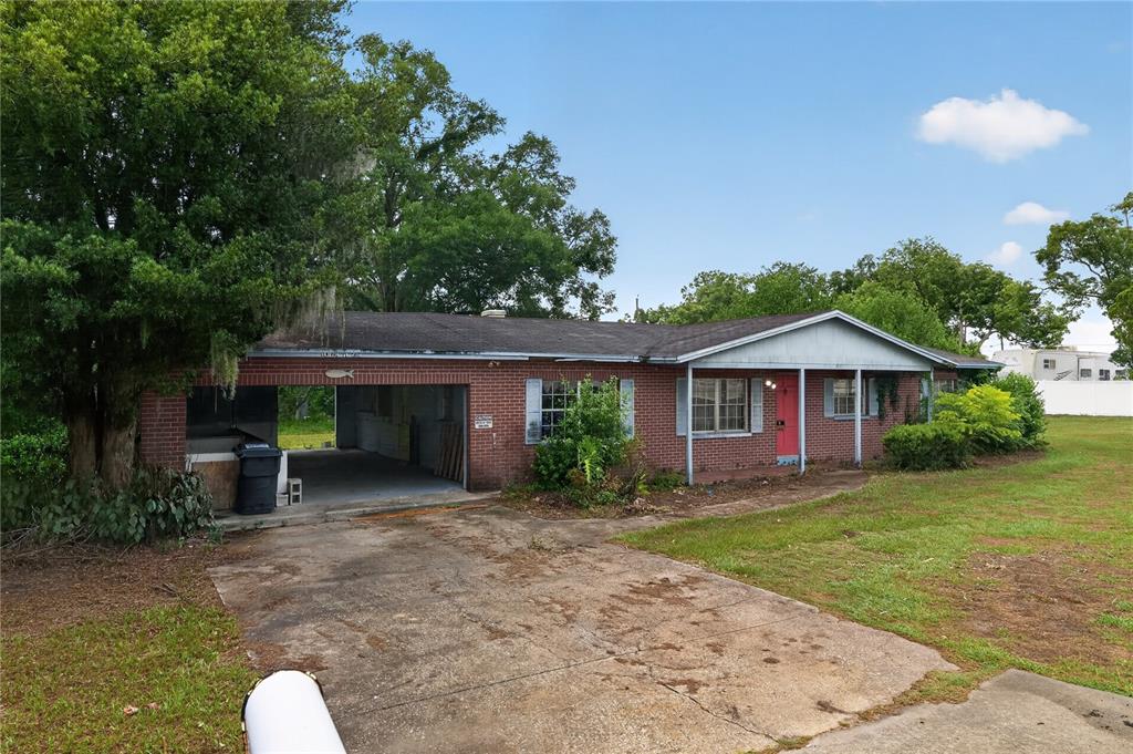 A single-story brick house features a carport, a pink front door, and a concrete driveway — 4315 E COUNTY ROAD 540A, LAKELAND, FL
