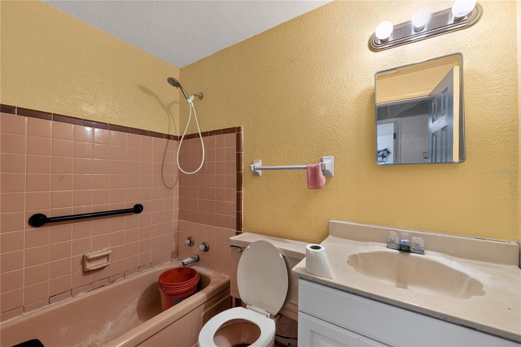 A bathroom features a pink tiled bathtub, a yellow wall, and a white vanity sink — 4315 E COUNTY ROAD 540A, LAKELAND, FL
