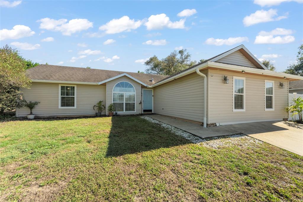 A screened-in swimming pool with a patio, lounge chair, and umbrella under a metal frame — 961 MILLENBECK AVENUE, DELTONA, FL
