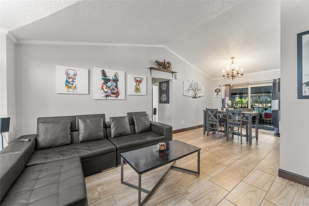 A living room with a black sectional sofa, coffee table, and an adjacent dining area — 961 MILLENBECK AVENUE, DELTONA, FL