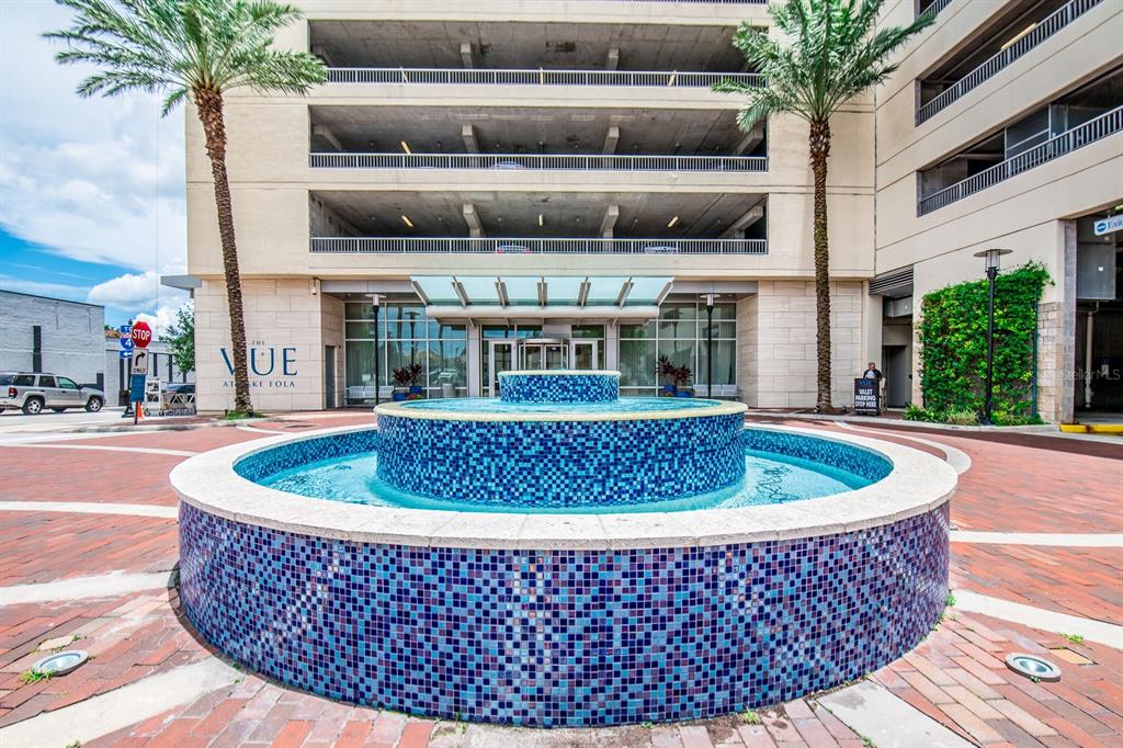 A multi-tiered blue tiled fountain sits in front of a modern building with parking levels — 150 E ROBINSON STREET UNIT 1810, ORLANDO, FL