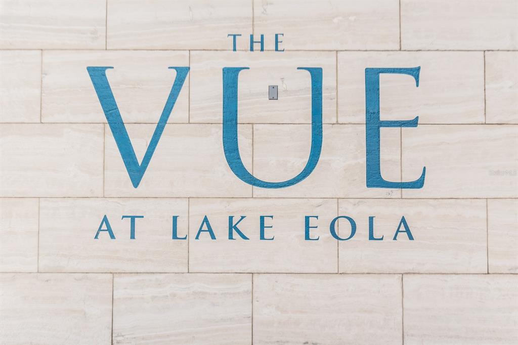 The blue text "THE VUE AT LAKE EOLA" is mounted on a light-colored stone wall — 150 E ROBINSON STREET UNIT 1810, ORLANDO, FL
