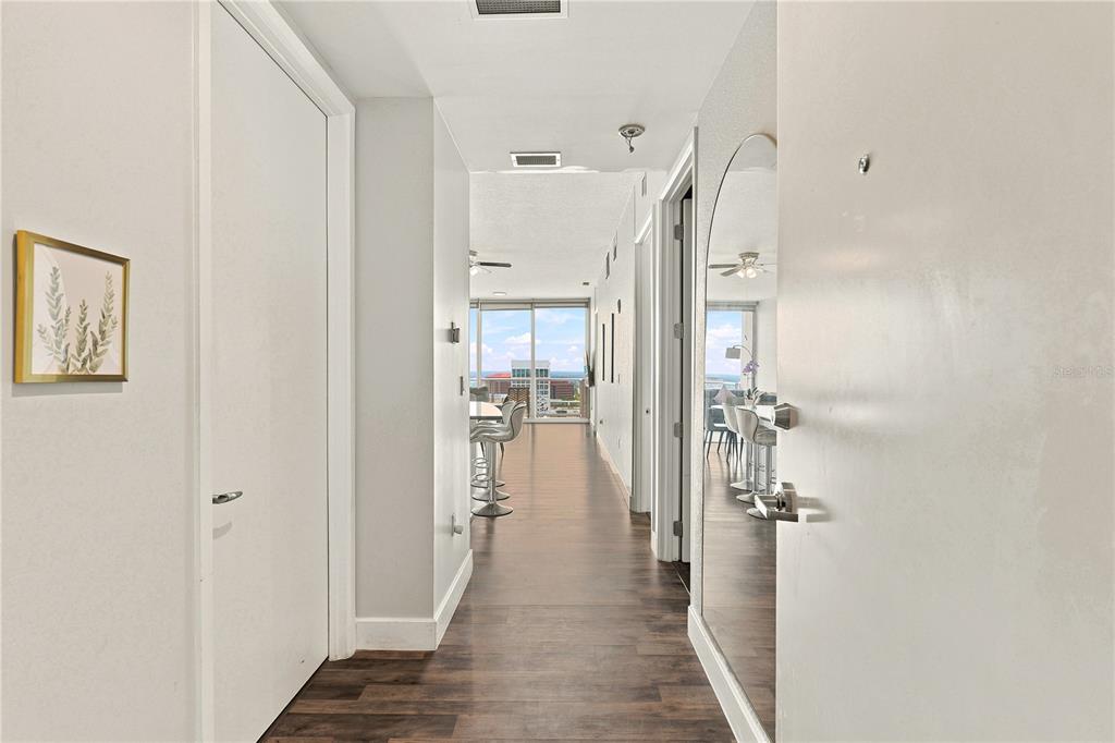 A hallway with wood-look flooring leads toward an open living area with a balcony view — 150 E ROBINSON STREET UNIT 1810, ORLANDO, FL