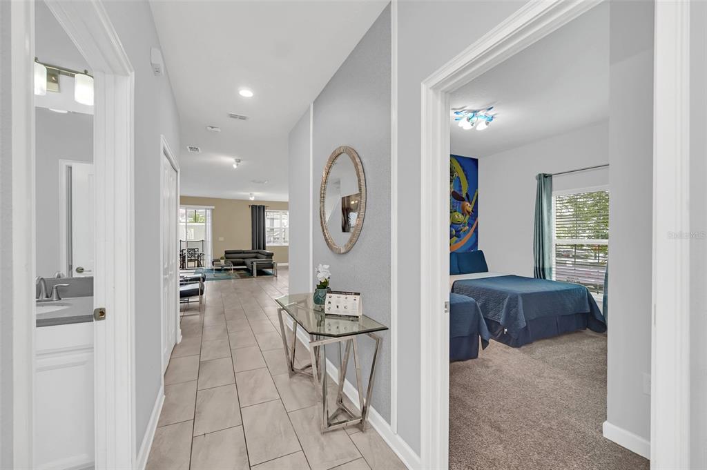 A hallway with tile flooring leads to a living area, with a bedroom to the right — 9017 DOGLEG DRIVE, DAVENPORT, FL