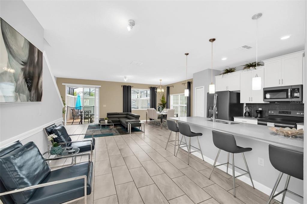 An open-concept living and dining area with a kitchen island and modern tile flooring — 9017 DOGLEG DRIVE, DAVENPORT, FL