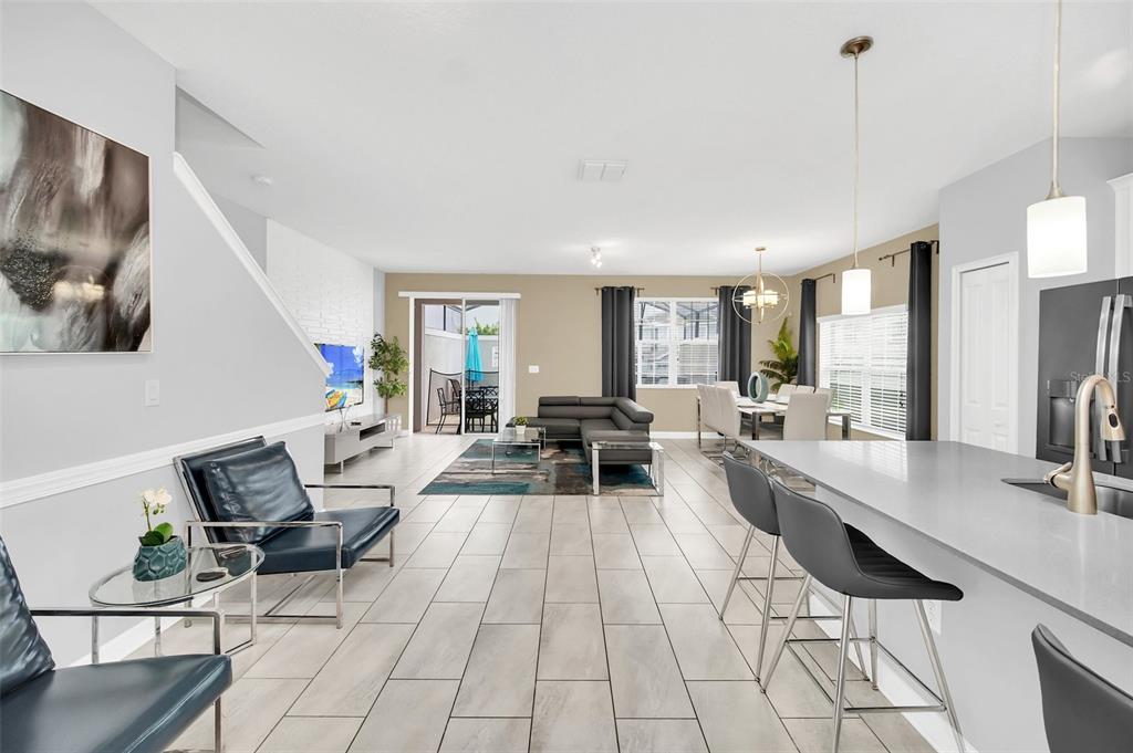 An open-concept living and dining area features tile flooring, a kitchen island, and sliding doors — 9017 DOGLEG DRIVE, DAVENPORT, FL