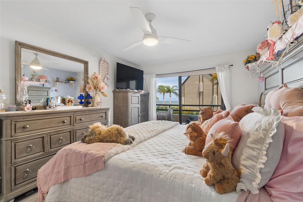 A bedroom features a bed with plush toys, a wooden dresser, and a balcony view — 103 1ST STREET E UNIT 115, ST PETERSBURG, FL