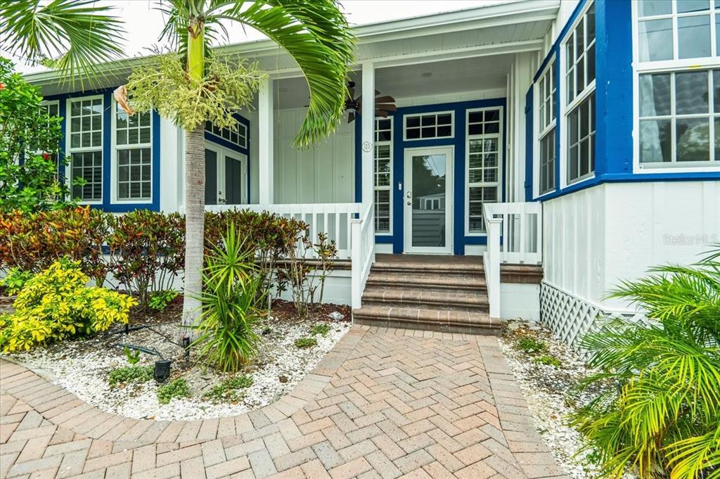 A brick walkway leads to the covered front porch and entrance of a white house — 115 EDMONDSON AVENUE, SARASOTA, FL
