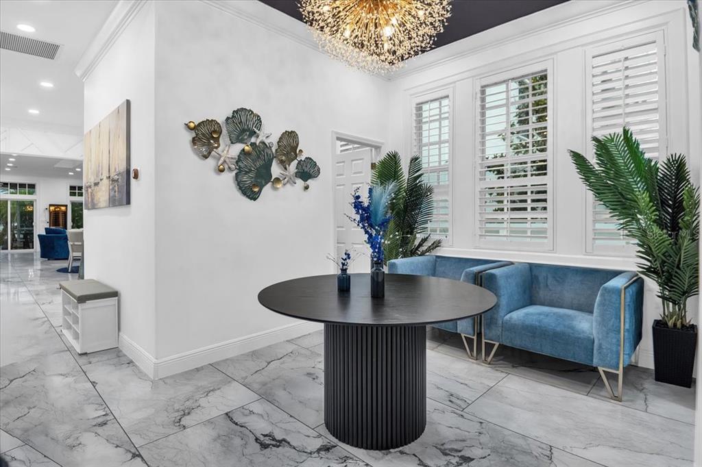 A bright foyer features a round black table, blue velvet chairs, and marble-look tile flooring — 115 EDMONDSON AVENUE, SARASOTA, FL