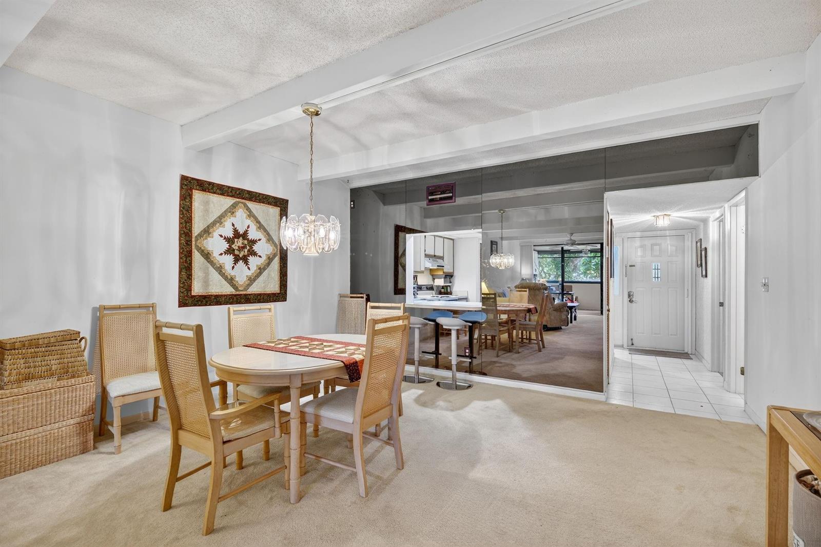 A dining area with a round table, cane chairs, and a large mirrored wall — 240 Hammock Shore Drive # 107, Melbourne Beach FL 32951, MELBOURNE BEACH, FL