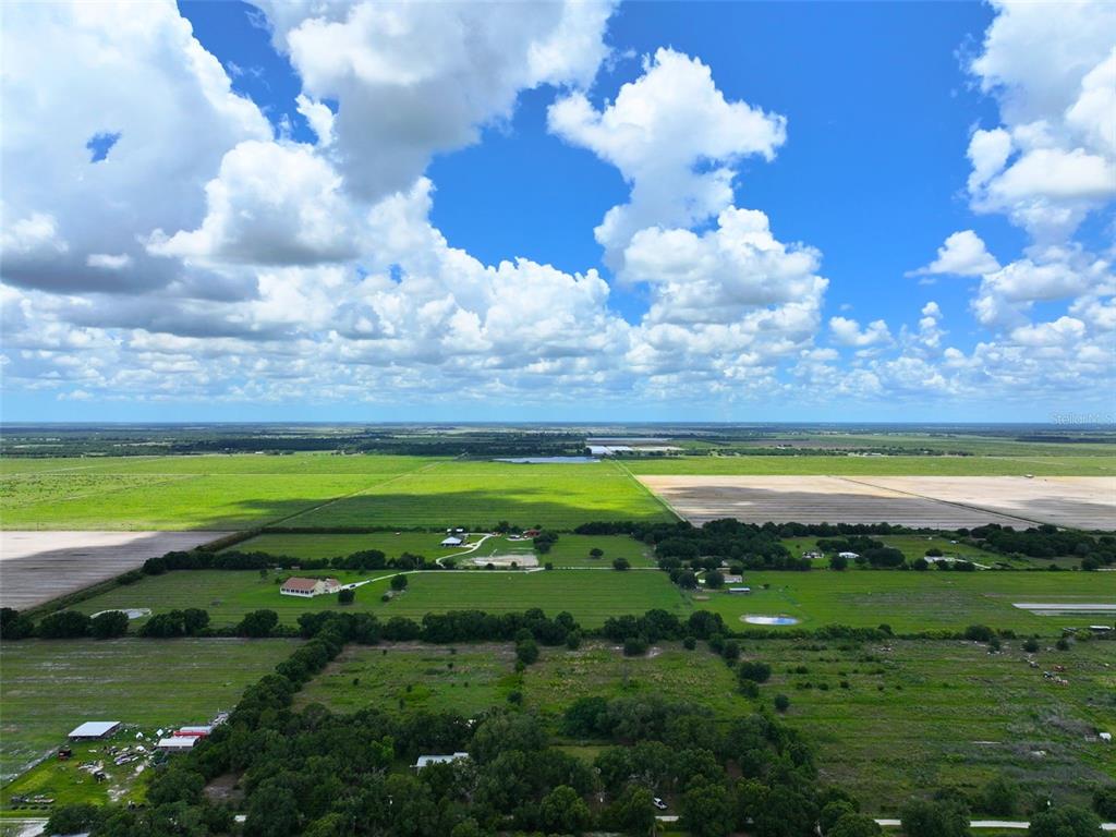 An aerial view shows a large rural property with green fields, scattered trees, and buildings — 9827 SE HOTH ROAD, ARCADIA, FL