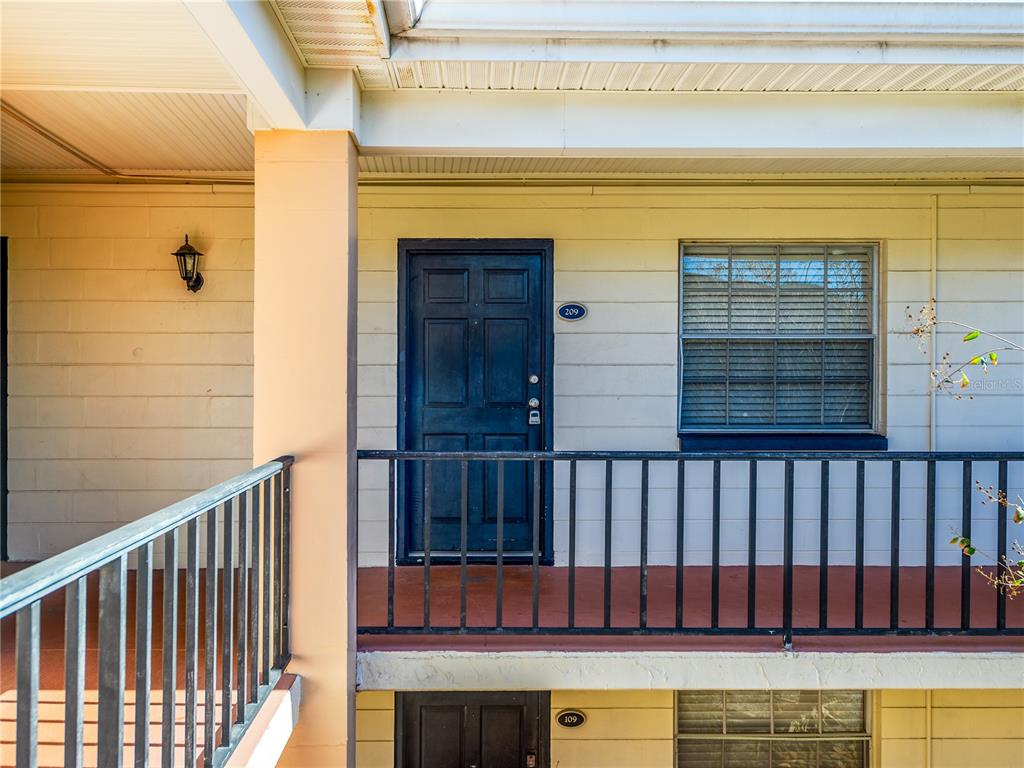 An exterior view of a two-story building featuring a dark door labeled 209 — 120 S CHURCH AVENUE UNIT 209, TAMPA, FL