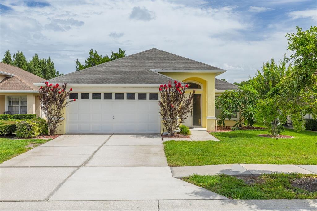 A yellow single-story house with a two-car garage and a concrete driveway — 7843 CRAIGHURST LOOP, NEW PORT RICHEY, FL