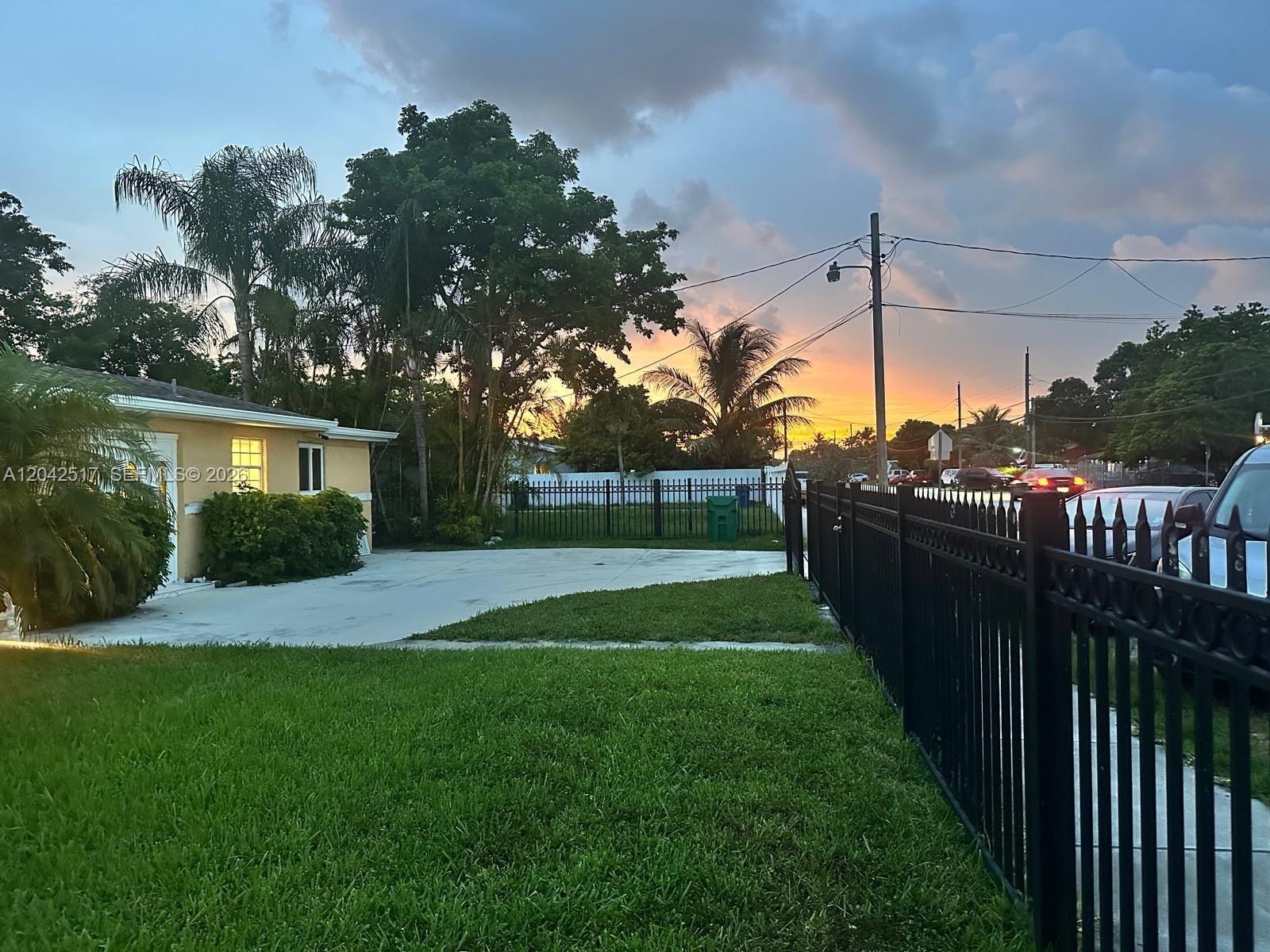A single-story house with a yellow exterior, a front lawn, and a paved driveway — MIAMI, FL