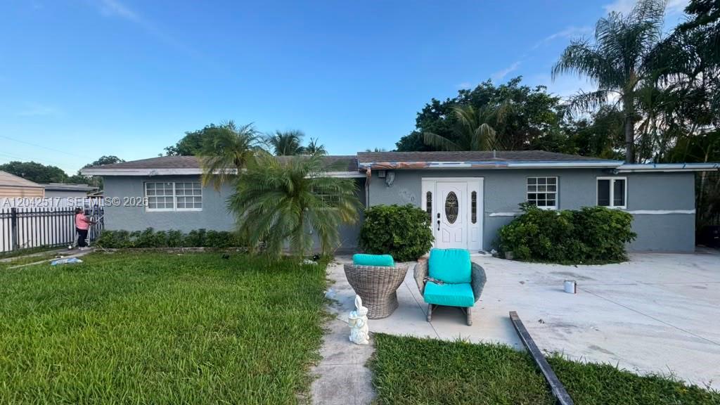 A residential house exterior with a driveway, lawn, and black metal fencing at sunset — MIAMI, FL