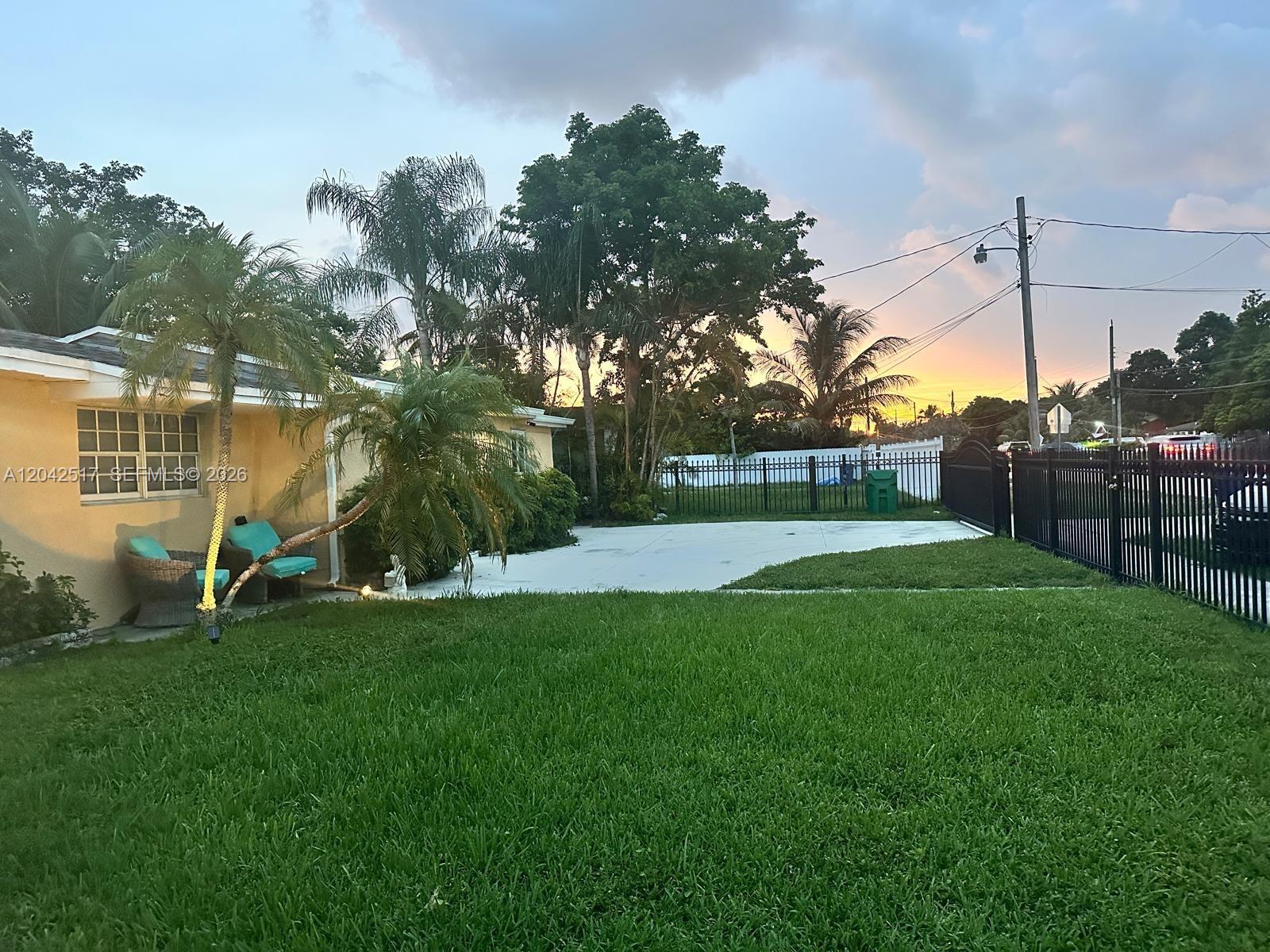 A single-story gray house with a white front door and a paved front patio area — MIAMI, FL