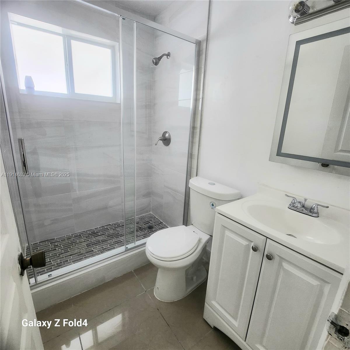 A bathroom features a glass-enclosed shower, a white toilet, and a vanity with a mirror — 2400 NW 10th Ave # 4, Miami FL 33127, MIAMI, FL